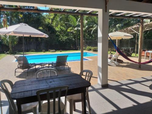 a patio with a table and chairs and a pool at Bèlla Chacara Morretes - Pr in Morretes