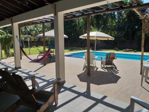 a patio with chairs and an umbrella and a pool at Bèlla Chacara Morretes - Pr in Morretes