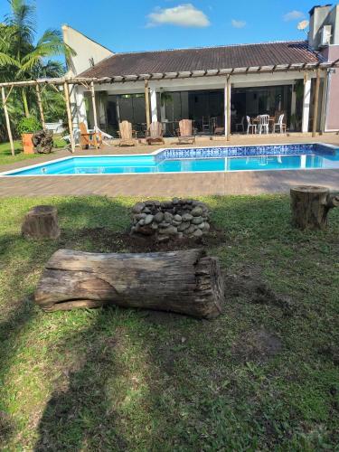 a log sitting in the grass next to a house at Bèlla Chacara Morretes - Pr in Morretes