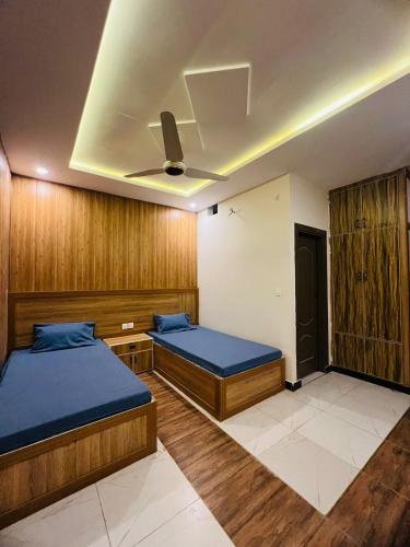 dwa łóżka w pokoju z drewnianymi panelami w obiekcie Noors B&B w mieście Islamabad