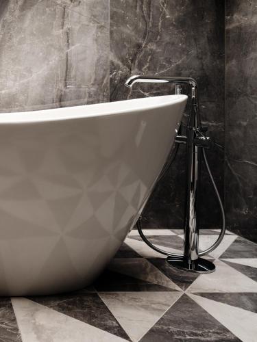 a white bath tub sitting on a tiled floor in a bathroom at The Crown Krakow Center - Handwritten Collection ACCOR in Kraków