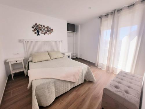 a white bedroom with a bed and a chair at Vive el Renacimiento: Ochío in Baeza