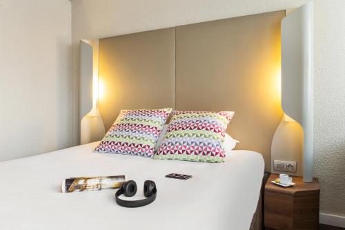 a bedroom with a bed with two pillows and a magazine at Campanile Dreux in Dreux