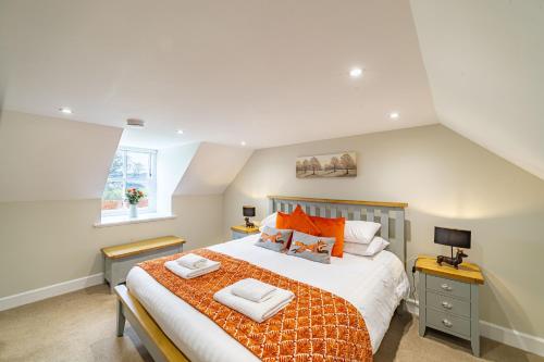 a bedroom with a large bed with orange pillows at Gardener’s Cottage with Hot Tub in Blairgowrie