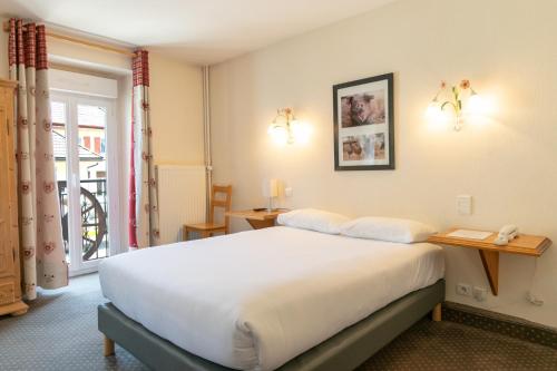 a bedroom with a large white bed and a window at Hôtel de la Poste in Malbuisson
