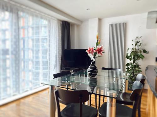 a glass table with a vase of flowers on it at Canary Wharf - Luxury Apartments in London