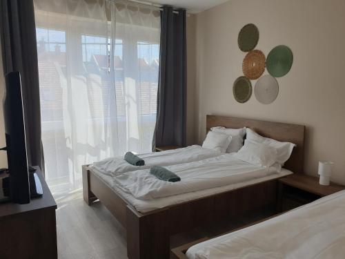 a bedroom with two beds and a large window at Chill House Apartman Eger in Eger