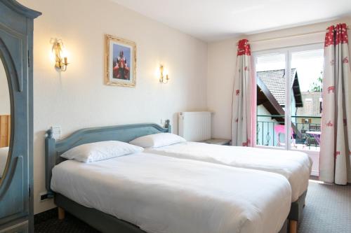 two beds in a hotel room with a window at Hôtel de la Poste in Malbuisson