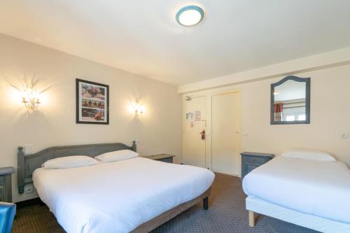 a bedroom with two beds and a mirror at Hôtel de la Poste in Malbuisson