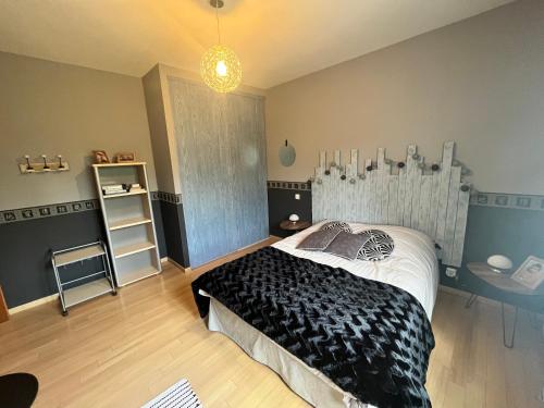 a bedroom with a bed with a black comforter at La rocaille 3 chambres doubles in Fondettes