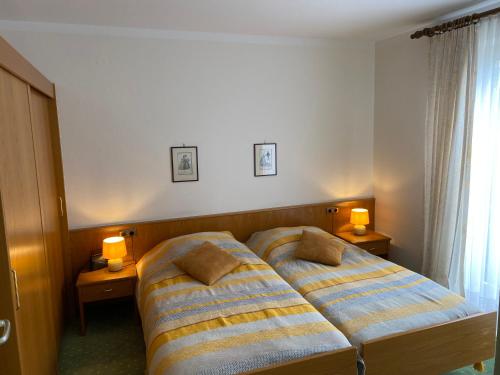 two beds in a hotel room with two lamps at Appartements Gloeser in Badenweiler