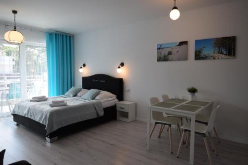 a bedroom with a bed and a table with chairs at Apartament Sweet Home Pogorzelica in Pogorzelica