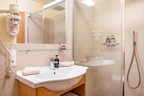 Un baño blanco con lavabo y ducha. en Hänsel und Gretel Schlosshof, en Umes