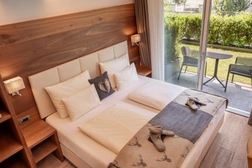 a bedroom with a bed and a balcony with a table at Arya Alpine Lodge in Selva di Val Gardena