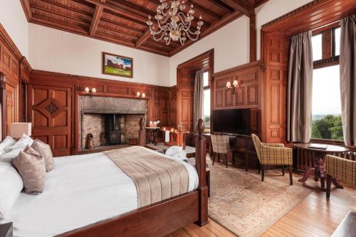 a bedroom with a large bed and a fireplace at Tulloch Castle Hotel ‘A Bespoke Hotel’ in Dingwall