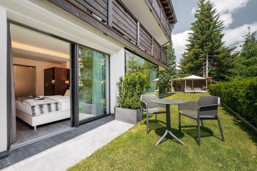 a patio with a table and chairs and a bedroom at Arya Alpine Lodge in Selva di Val Gardena