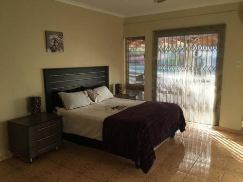 Un dormitorio con una cama grande y una ventana grande. en Mphesheleng Guesthouse, en Bela-Bela