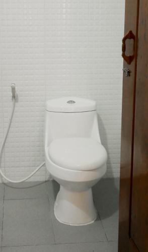 a white toilet in a bathroom with a hose at Nary Garden in Kampot