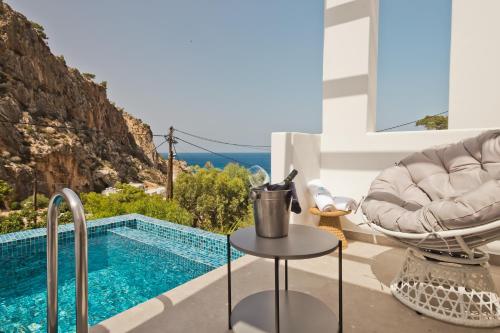 a villa with a pool and a chair and a table at Enilion Luxury Suites in Karpathos