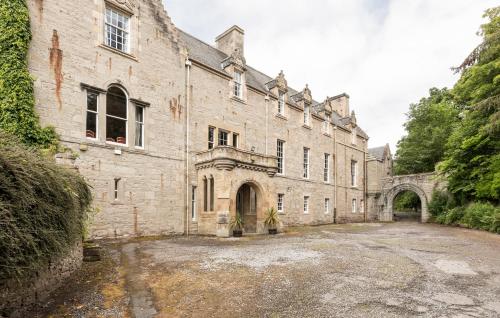 an old stone building with a driveway in front of it at Tulloch Castle Hotel ‘A Bespoke Hotel’ in Dingwall