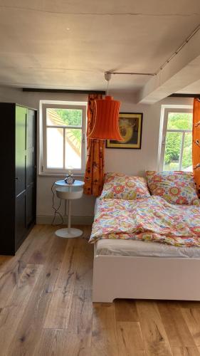 een slaapkamer met een bed, een tafel en 2 ramen bij Bauernhaus in der Bayrischen Rhön in Schönau an der Brend