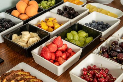 a table topped with bowls of fruits and vegetables at Arya Alpine Lodge in Selva di Val Gardena