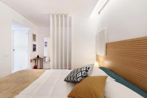 Schlafzimmer mit einem großen Bett mit einem Kopfteil aus Holz in der Unterkunft Estoril Art and Surf in Estoril