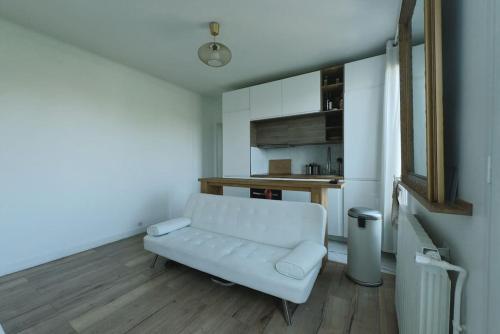 een woonkamer met een witte bank en een keuken bij Charmant appartement à 2 pas de Paris in Saint-Maur-des-Fossés