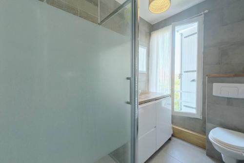 baño con aseo y puerta de ducha de cristal en Charmant appartement à 2 pas de Paris, en Saint-Maur-des-Fossés
