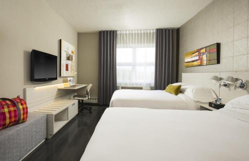 a hotel room with two beds and a tv at Hotel Sepia in Quebec City