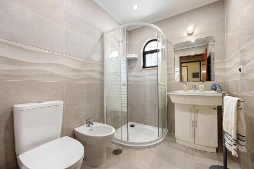 a bathroom with a toilet and a shower and a sink at Casa Palmeira in Armação de Pêra