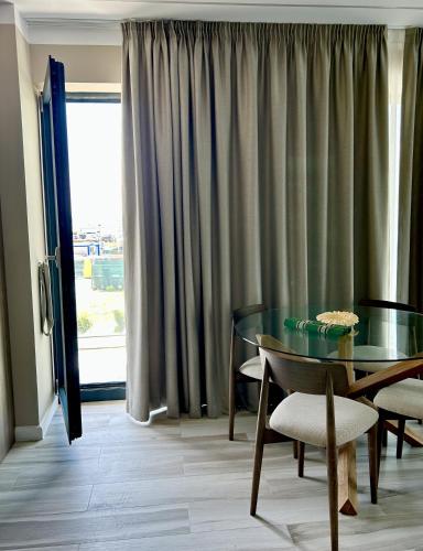 a dining room with a glass table and chairs and a window at Seaside Apartment in Mamaia