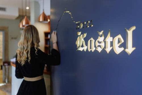 a woman is standing next to a wall with a sign at Boutique Hotel Kaštel in Motovun