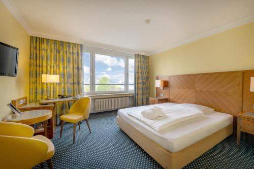 クレーフェルトにあるHotel Krefelder Hofのベッドと机と椅子があるホテルの部屋