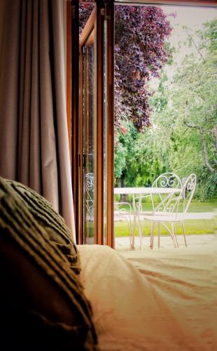 a bed in front of a window with a table and bench at Cosy One Bed Barn Conversion Donington Park East Midlands Airport in Derby