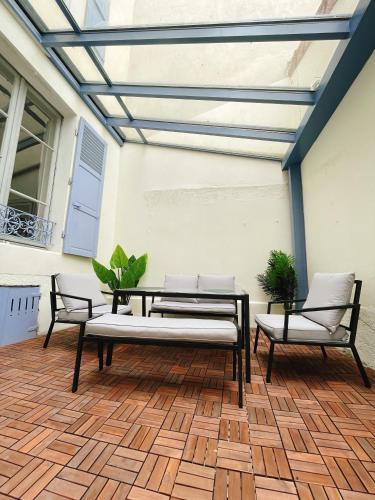un patio avec deux bancs, une table et des chaises dans l'établissement Villa muguette - coeur de Vichy- RDC-véranda sur la terrasse, à Vichy