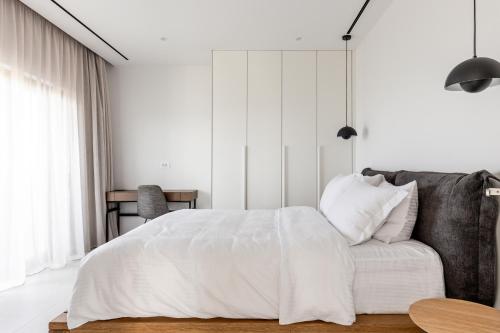 Habitación blanca con cama y sofá en NOLA - Nomadic Luxury Villas en Gouves