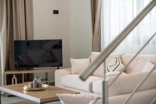 a living room with a white couch and a television at Vathy Villas in Preveza