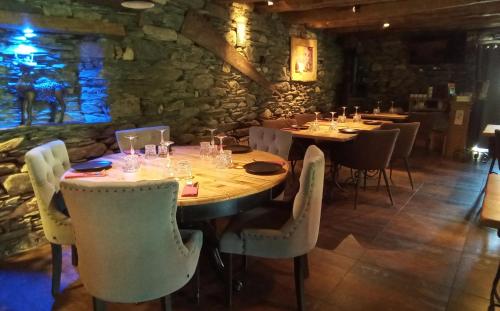 a restaurant with tables and chairs and a stone wall at L' Auberge du château in Génos