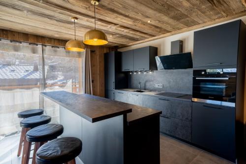 uma cozinha com um balcão e alguns bancos em Appartement Les Myrtilles - pied des pistes - 10 personnes em Les Deux Alpes