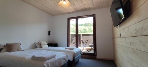 a bedroom with two beds and a large window at Résidence Le Sommet in Les Hôpitaux-Neufs