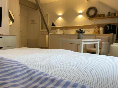 a bedroom with a white bed and a kitchen at Weberhof - Münster 6 in Münster