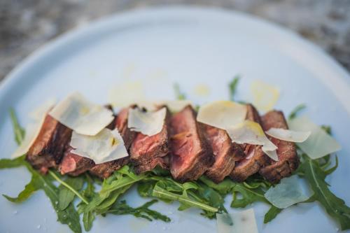 a plate of food with meat and greens on it at Boutique Hotel Kaštel in Motovun