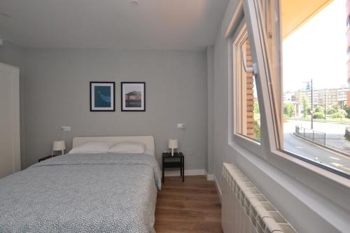 sypialnia z łóżkiem i dużym oknem w obiekcie STAY Las Segadas w mieście Oviedo