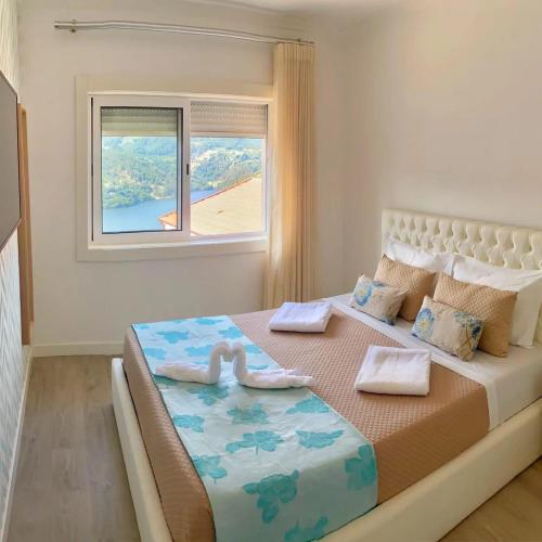 a bedroom with a large bed with a window at Refúgio Douro abelhal in Santa Cruz do Douro