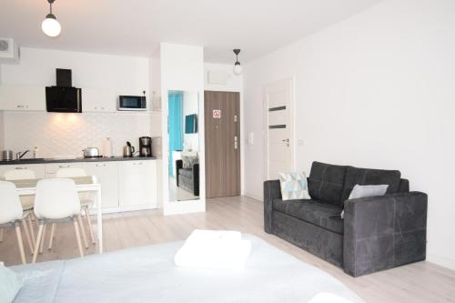 a living room with a black couch and a kitchen at Apartament Sweet Home Pogorzelica in Pogorzelica