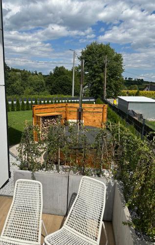 two white chairs sitting next to a garden with plants at HamakoweLove in Dąbrówka