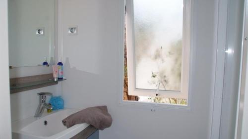 une salle de bain blanche avec un lavabo et une fenêtre dans l'établissement MOBILOCAMP, au Muy