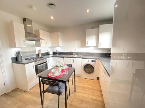 a kitchen with white cabinets and a table and a stove at Luxurious and Spacious 2 Bedroom Flat in Milton Keynes