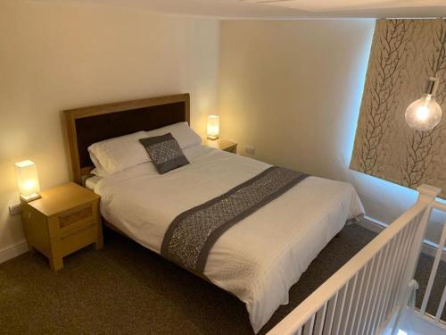 a bedroom with a large bed with two lights on it at Skippings in Beccles